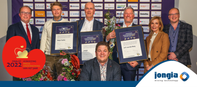 Seven people stand smiling in front of a sponsor wall, holding framed certificates and flowers. A badge reads “Finalist 2022 Verkiezing Friese Onderneming van het Jaar.” The Jongia Mixing Technology logo appears at the bottom right.