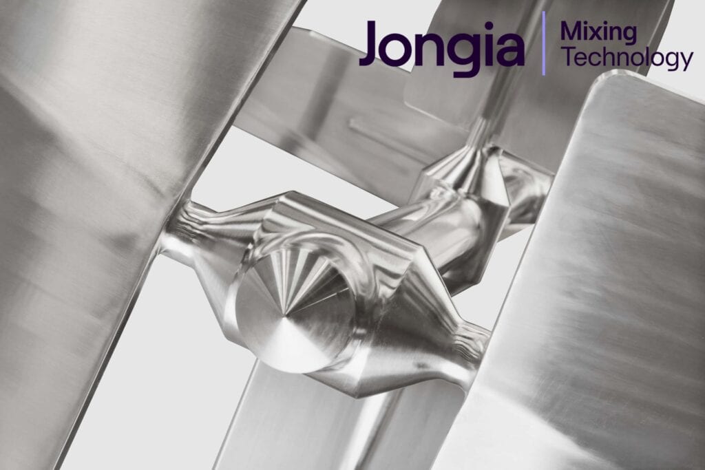Close-up of a shiny stainless steel industrial mixer blade with angular surfaces. The background is light gray. In the top right corner, the purple text reads Jongia Mixing Technology. The overall look is clean and modern.