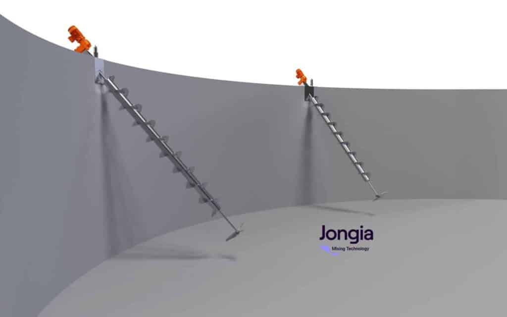 Two metal auger-style mixers are installed diagonally inside a large, upright, gray cylindrical tank. Each mixer is mounted at an angle through the tank’s upper wall, with orange motors attached on top. The tank interior is empty and well-lit.