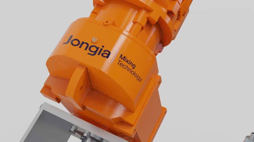 Close-up of an industrial orange machine part with Jongia Mixing Technology labeled on its side, showing bolts and structural details against a plain, light gray background. The equipment appears sturdy and is likely used for mixing processes.