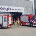 Two fire engines parked outside the Jongia De Dietrich building during Safety Day, with firefighters walking into the production hall.
