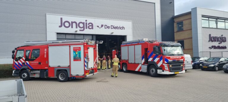 Two fire engines parked outside the Jongia De Dietrich building during Safety Day, with firefighters walking into the production hall.