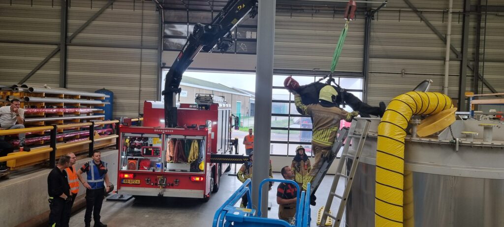 Firefighters use the crane of their fire engine to lift the victim out of a stainless steel storage tank during the rescue demonstration.