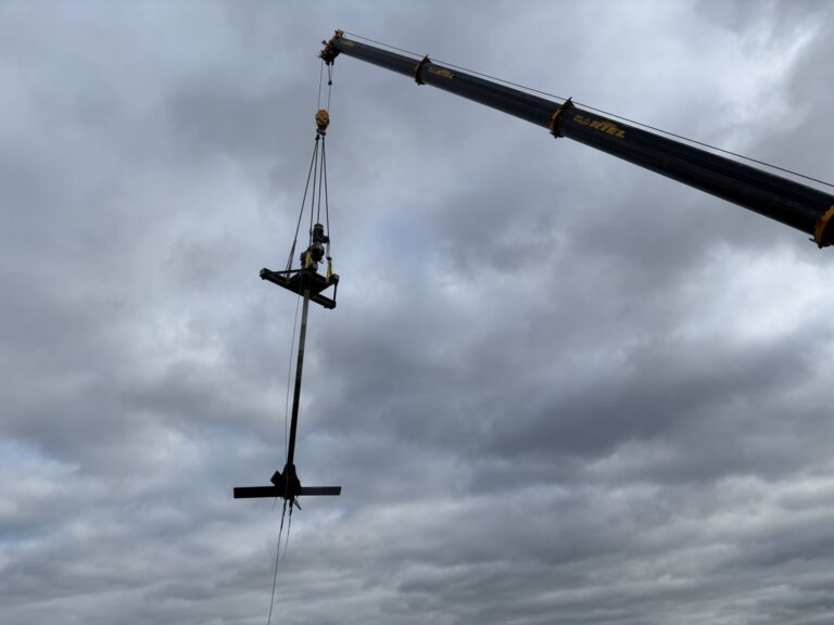 The complete Jongia agitator hangs from the crane boom against a cloudy sky.
