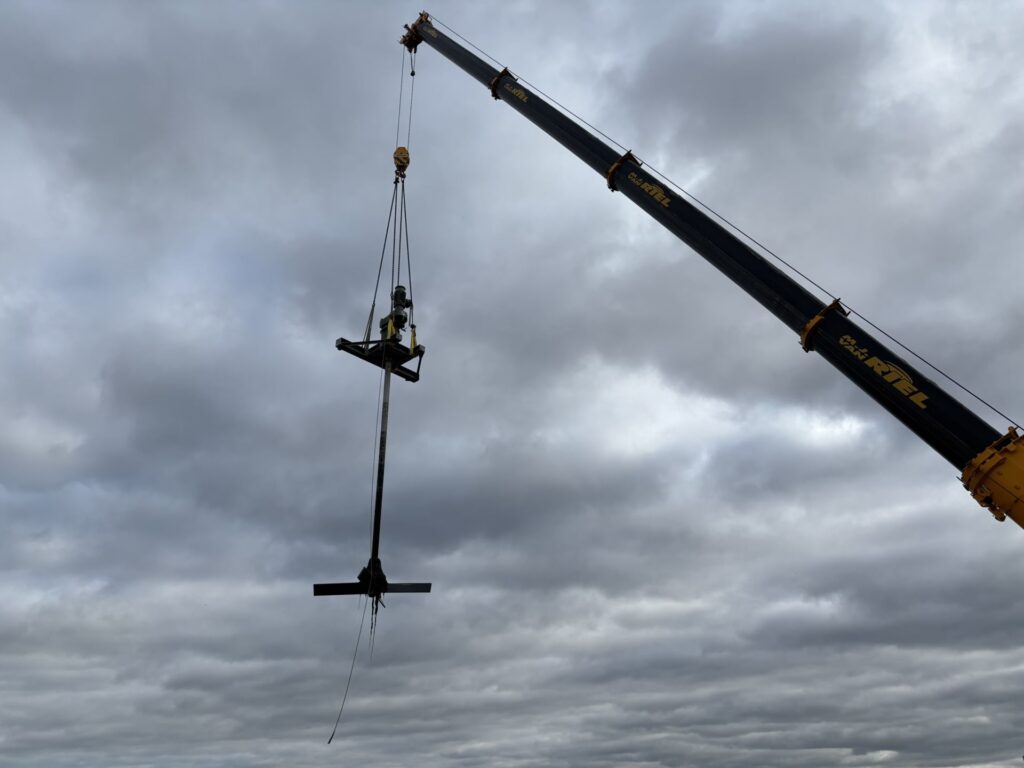 The complete Jongia agitator, with drive, long shaft and impeller, lifted high above WWTP Venlo by a mobile crane.